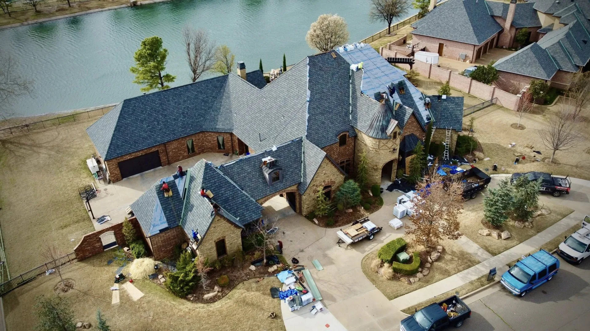 Aerial view of an Impact Construction crew re-roofing a large lakefront home